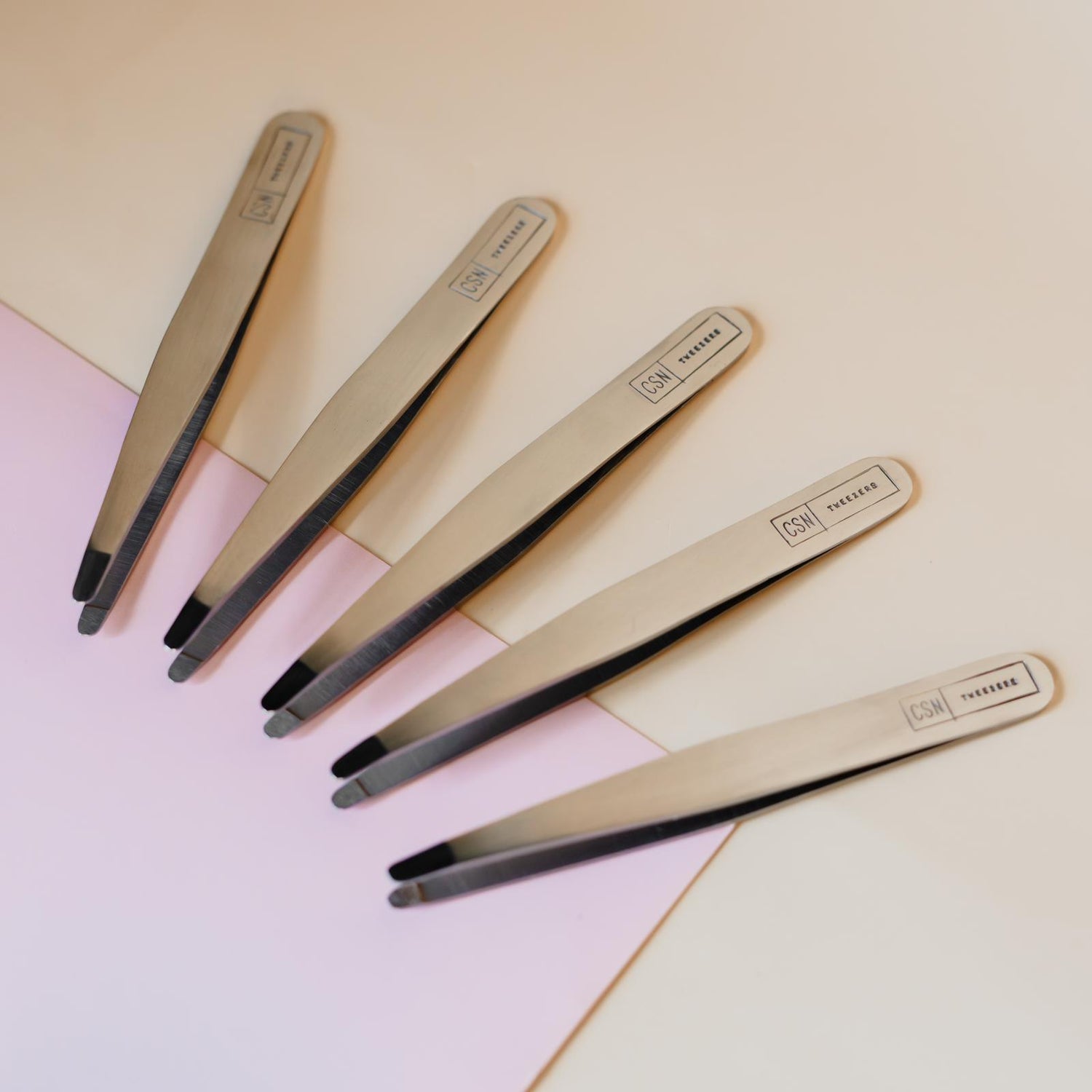 Afbeelding van 5 soorten Tweezers naast elkaar opgesteld inclusief het logo erop.